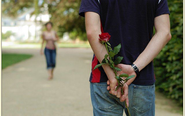 На 1 свидание предложил купить траву песня. Парень дарит розу на улице. Парень с цветами. Парень дарит девушке цветы. Цветы за спиной.