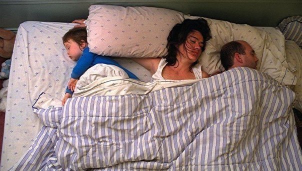 Мать легла спать сыном. Совместный сон с ребенком. Спят в одной кровати.