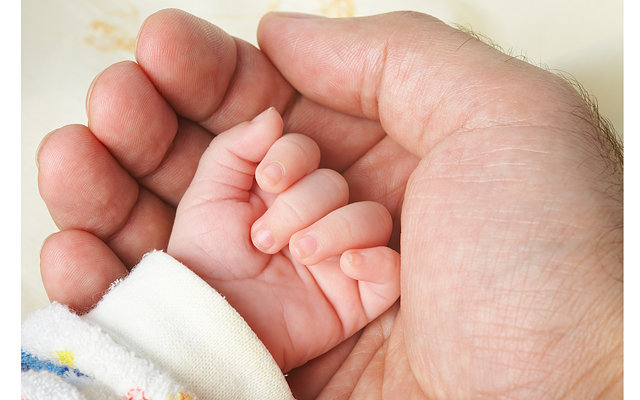 Ручка новорожденного мальчика на руке мамы