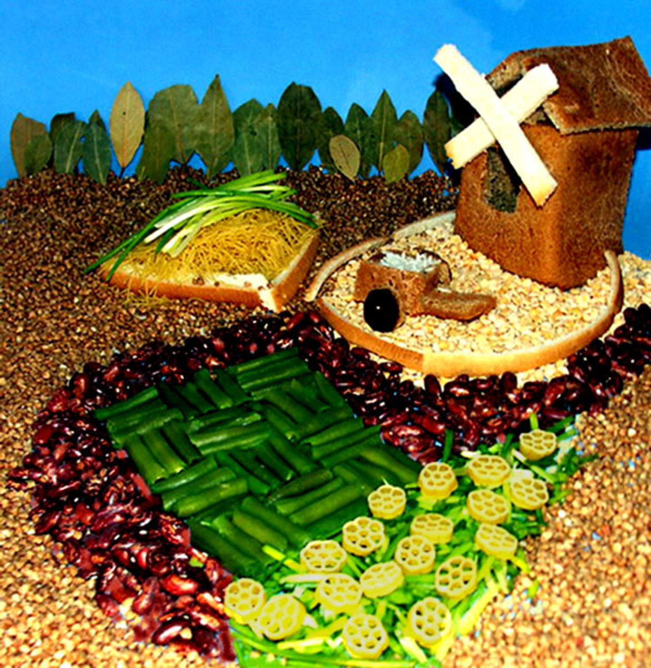 Деревенский летний пейзаж. На заднем плане деревья- лавровые листы. Мельница- ржаной хлеб и лопасти- пшеничный хлеб. Стог сена- вермишель и зеленый лук. Тележка- ржаной хлеб, в телеге –рис. Оградки- пшеничный хлеб. Дорожка- красная фасоль. Огороды- стручковая зеленая фасоль, зеленый лук и макароны-цветочки. Почва- горох, гречка.  Schauma